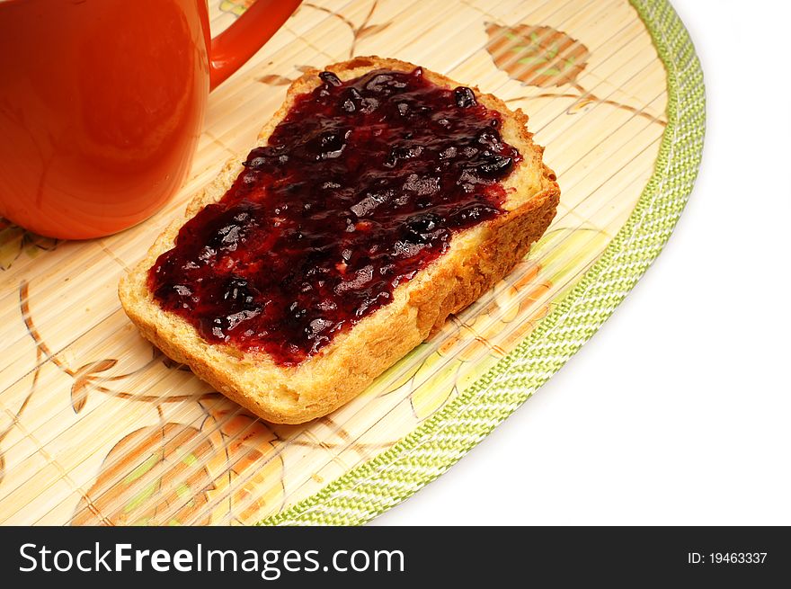 Slice of bread with jelly on placemat on white background