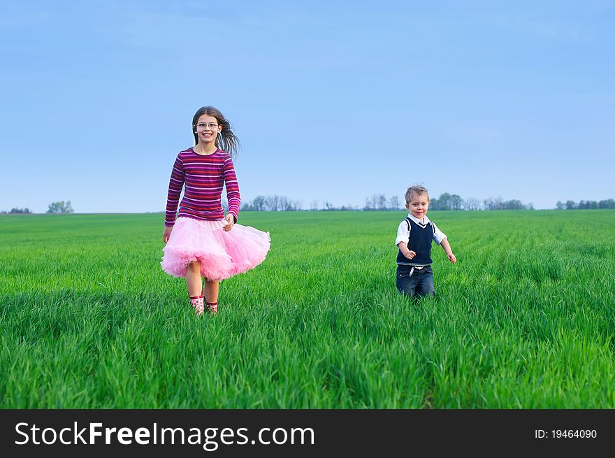 A beautiful sister runing with her cute little brather on the grass. A beautiful sister runing with her cute little brather on the grass