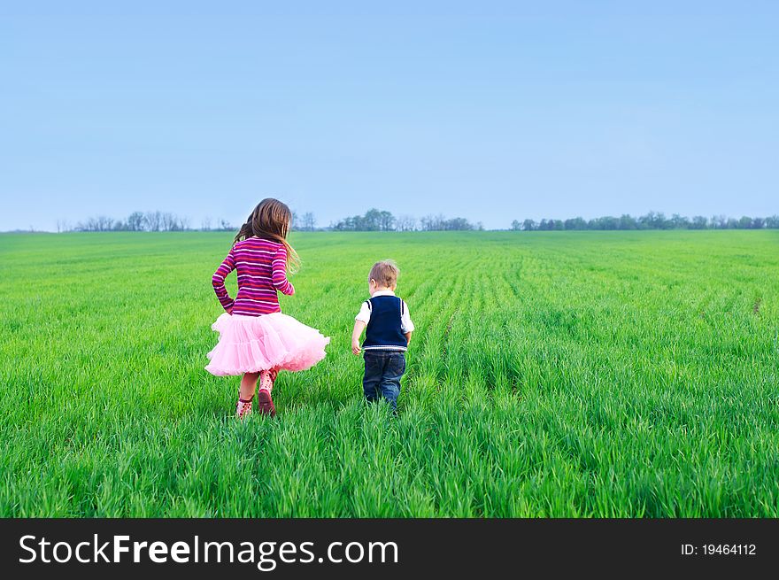 A beautiful sister runing with her cute little brather on the grass. A beautiful sister runing with her cute little brather on the grass