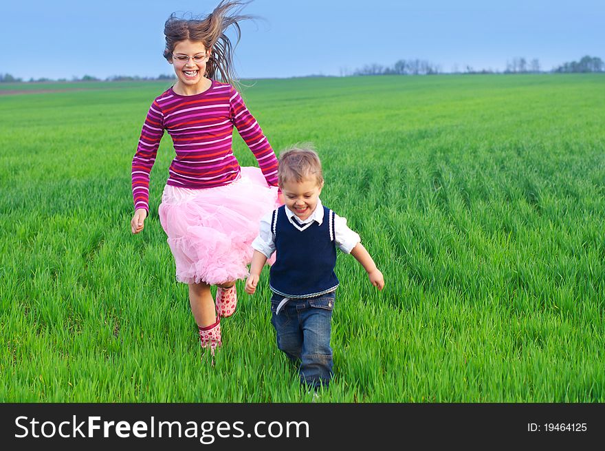 A beautiful sister runing with her cute little brather on the grass. A beautiful sister runing with her cute little brather on the grass