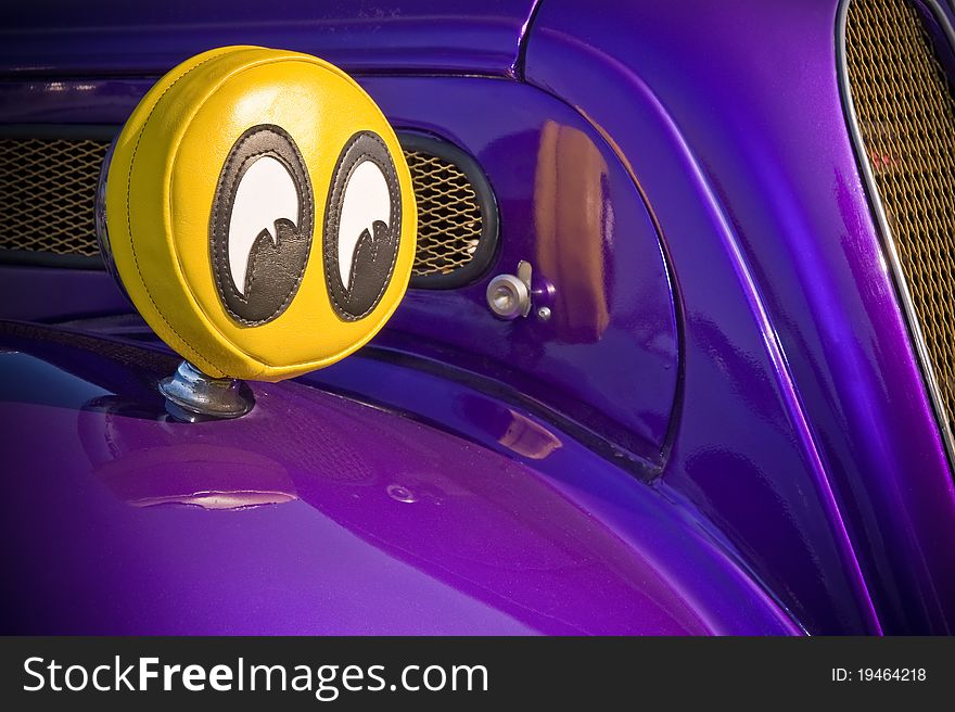 Humorous big eyes covering the headlights of a purple car