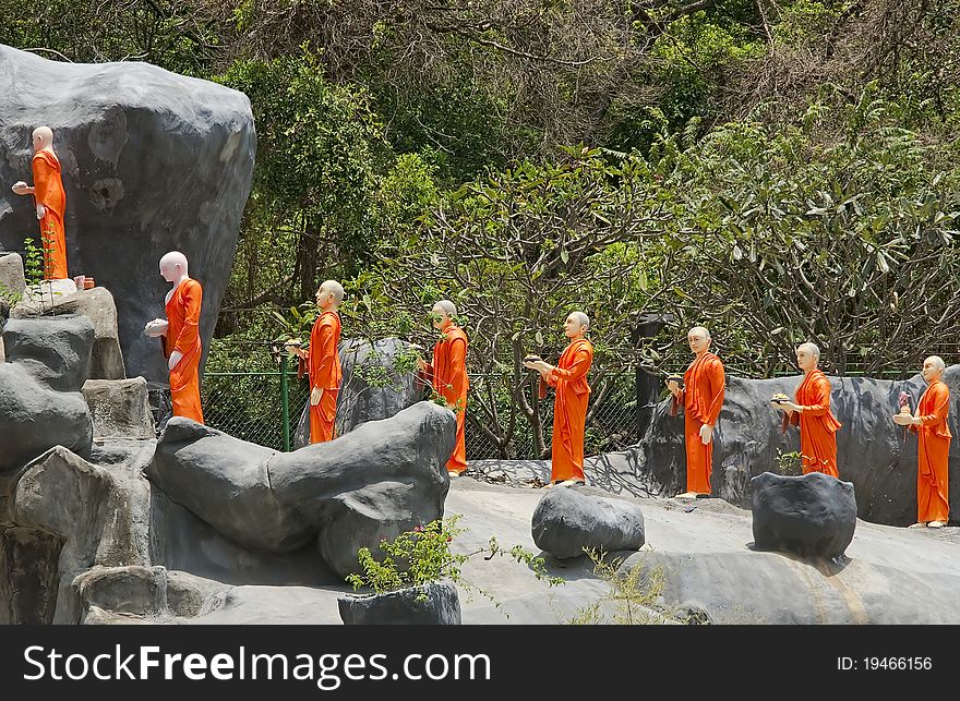 Figures of monakhs in orange dress stay on stone road. Figures of monakhs in orange dress stay on stone road