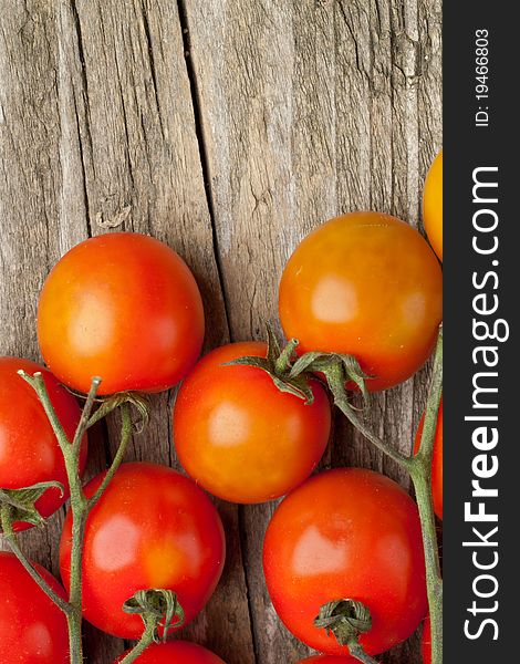 Branch of fresh cherry tomato on wooden background