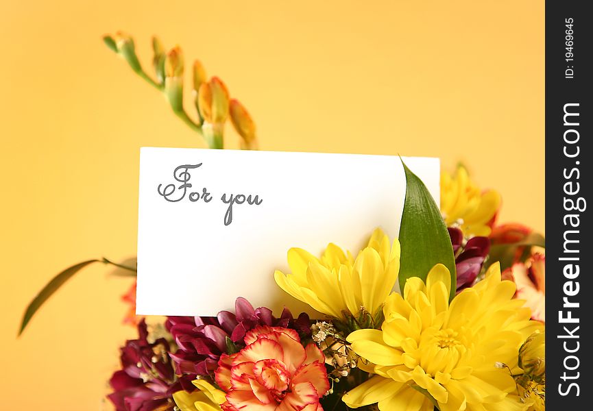 Bright flowers with card on yellow