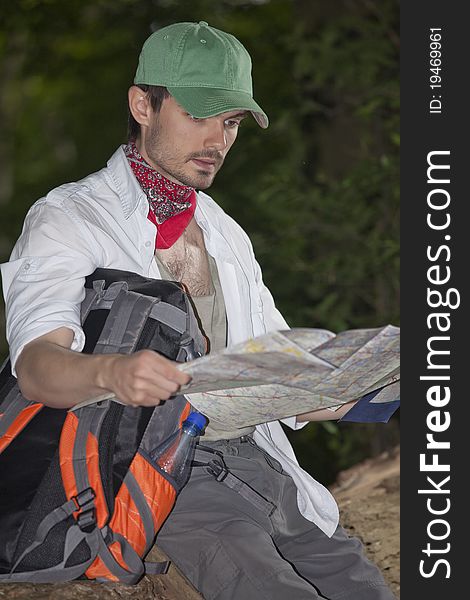 Male hiker with map sitting on the tree