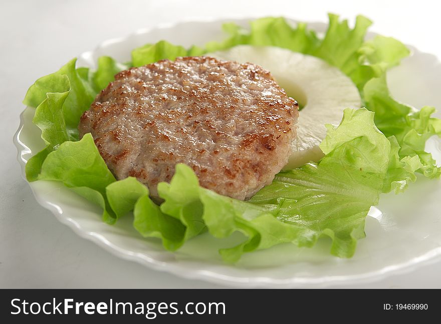 Meat rissole with lettuce and pineapple on the plate