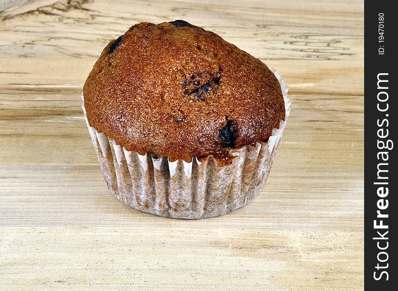 A Muffin on a wooden surface. Photographed in a studio.