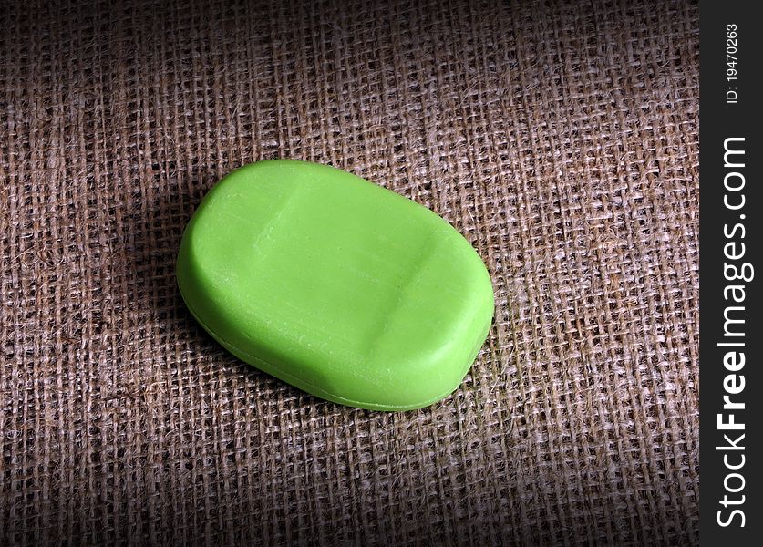 A low key image of a green cake of soap on a hessian background.