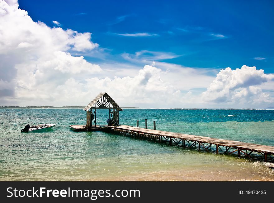 Motor boat at the pier, sea and blue sky with clouds on the horizon