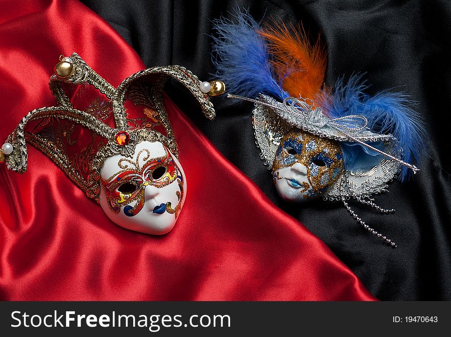 Two venetian mask on a black and red silk