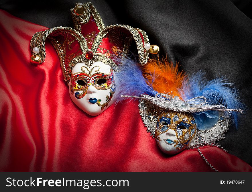 Two venetian mask on a black and red silk