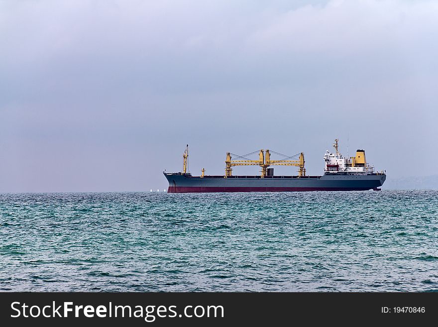 Cargo ship leaving port on a cloudy day. Cargo ship leaving port on a cloudy day