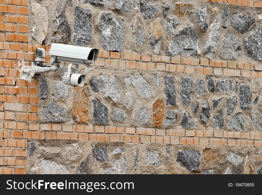 Security camera mounted on a stone and brick wall. Security camera mounted on a stone and brick wall
