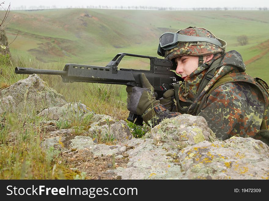 Young warrior hiding behind the rock with a gun. Young warrior hiding behind the rock with a gun