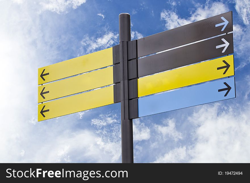 Colorful plastic informational signs with arrows. Show the direction. Against the blue sky with clouds