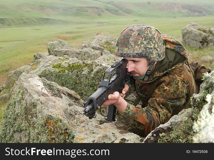 Warrior hiding behind the rock with a gun. Warrior hiding behind the rock with a gun