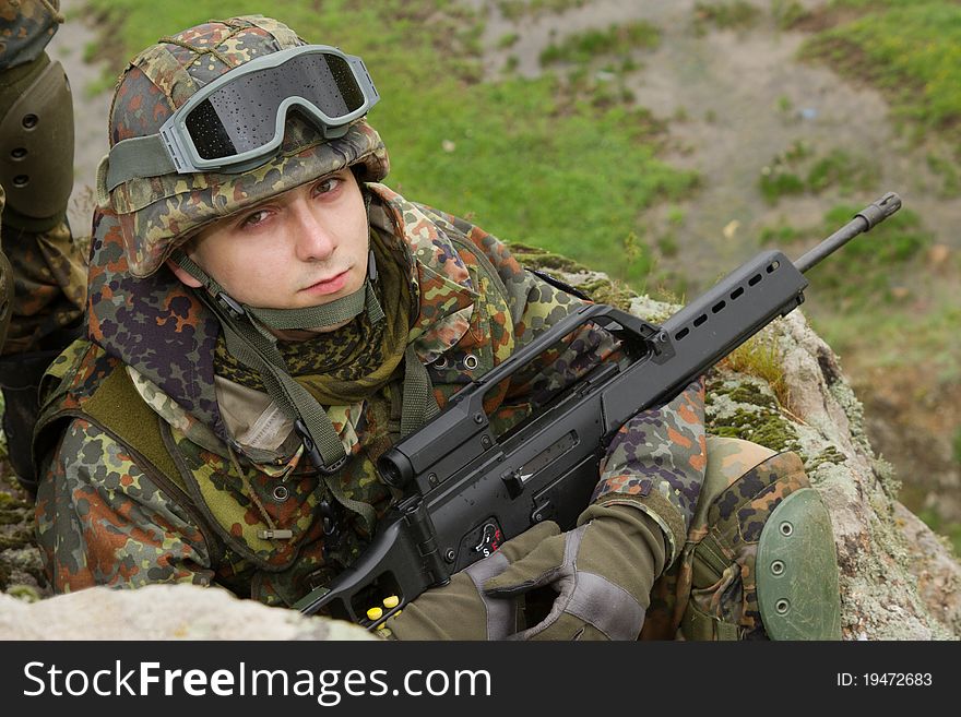 Portrait Of Young Soldier Sitting With A Rifle