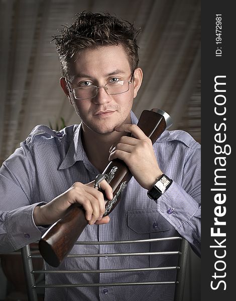 Classy romantic guy with glasses sitting on a chair with musket in his hands. Classy romantic guy with glasses sitting on a chair with musket in his hands.