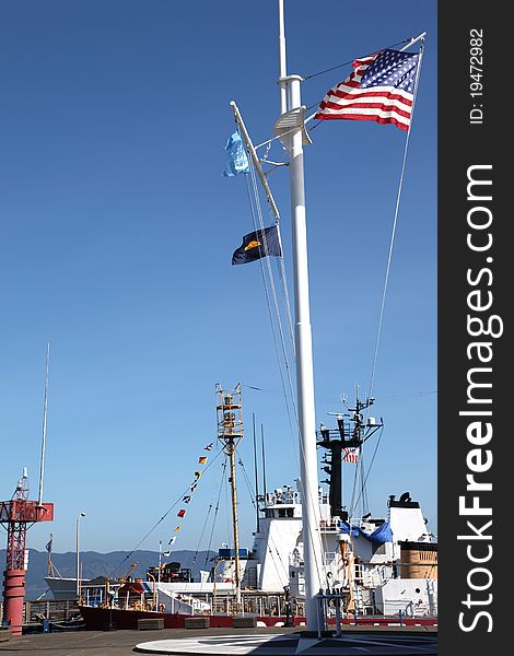 A coast guard ship docked and a mast with flags at the maritime museum in Astoria Oregon. A coast guard ship docked and a mast with flags at the maritime museum in Astoria Oregon.