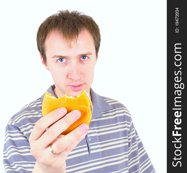 The young man eats a hamburger. Focus on hamburger.