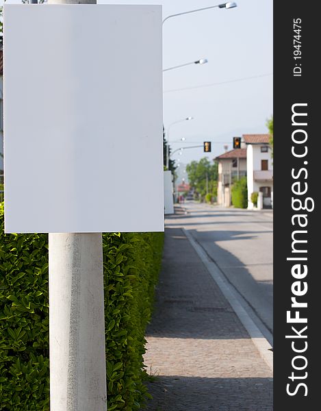 A white panel beside a street with traffic light in the background. A white panel beside a street with traffic light in the background