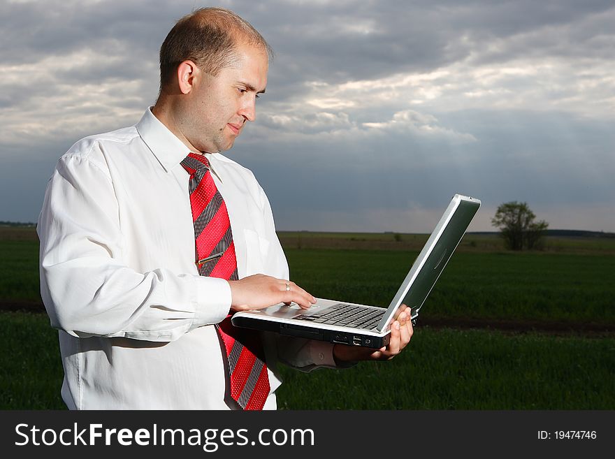 The young businessman has control over the computer against the nature. The young businessman has control over the computer against the nature