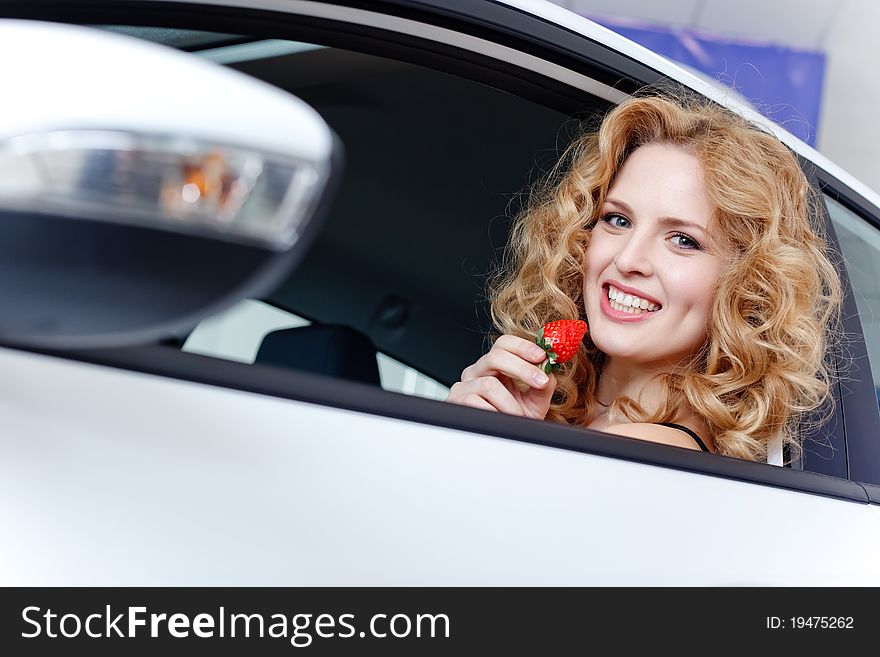 Young woman with strawberry in New car