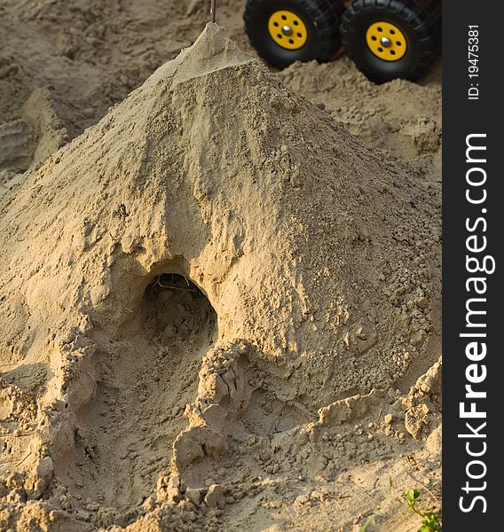 Sand castle with tunnel and car's wheel