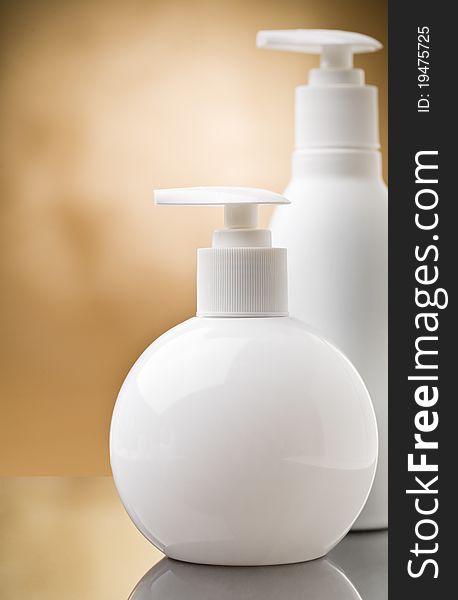 Copyspace view on two white round bottles on abstract brown background