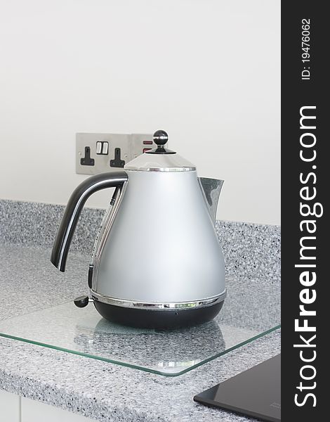 Modern grey metal kettle stood on a granite worktop. Modern grey metal kettle stood on a granite worktop
