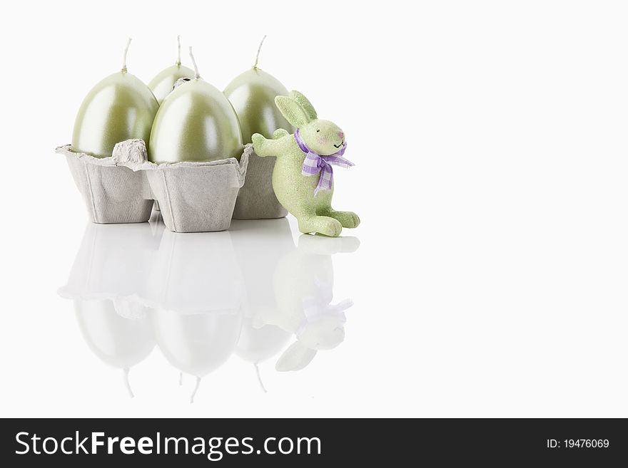 A green easter-bunny and four easter-candles on white background