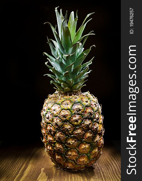 One pineapple on old wooden board