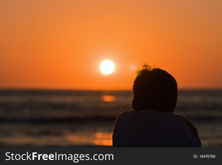 Silhouette of a boy watching sunset at the sea. Silhouette of a boy watching sunset at the sea