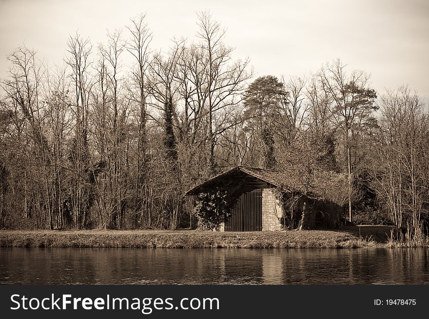 Old style shot of a shed on the riverside, all alone in the wood