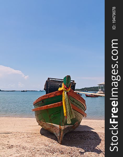 Wooden boat on the beach with beautiful blue sky in background in Thailand from front vertical