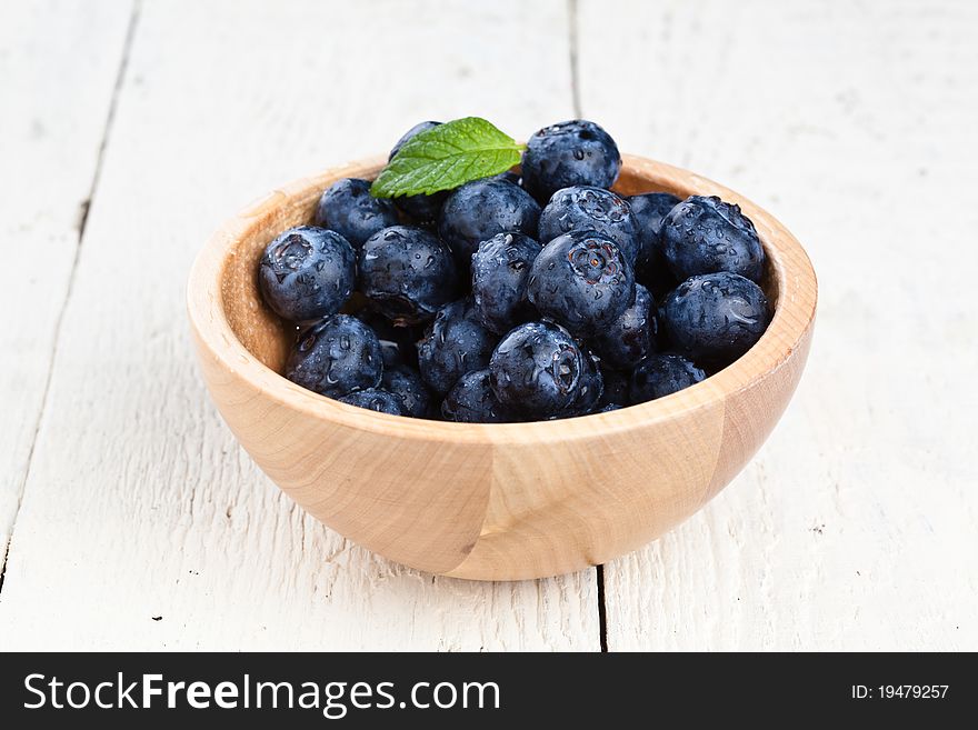 Blueberries in a small wooden dish on a wooden table. Blueberries in a small wooden dish on a wooden table