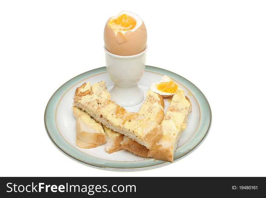 Soft boiled egg with buttered toast soldiers on a plate isolated against white