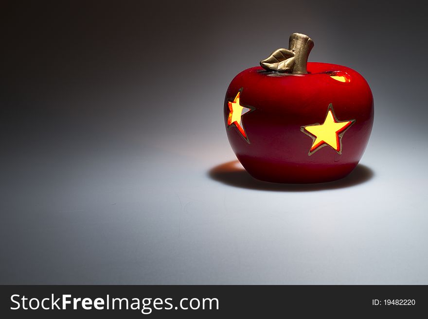 Decorative red apple with luminous stars c enigmatic illuminated from the top on black white background