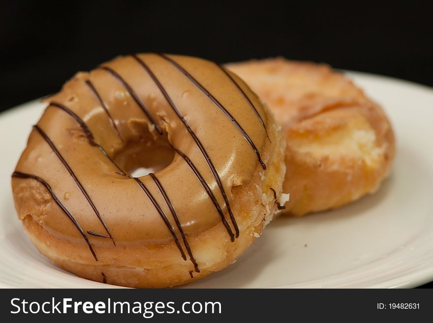 Peanut cream topping donuts in the white dish with dark isolated backgrond. Peanut cream topping donuts in the white dish with dark isolated backgrond