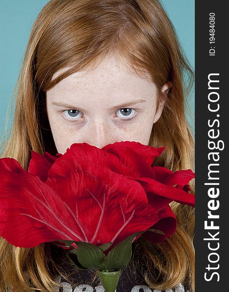 Young girl is looking at you over a big red rose