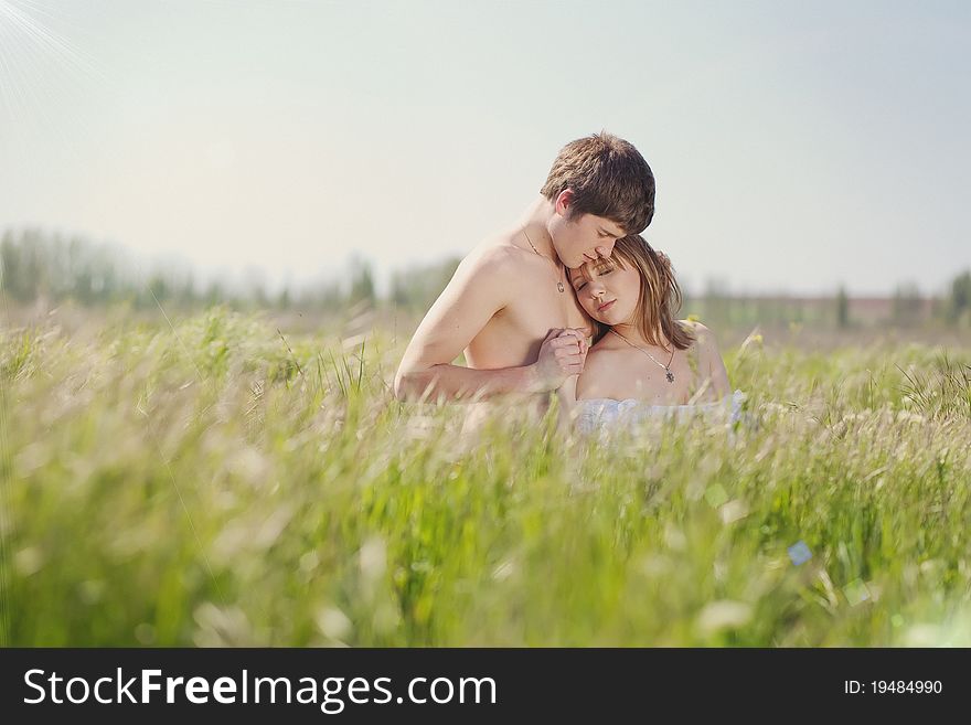 Beautiful young pair kissing and hugging on green grass