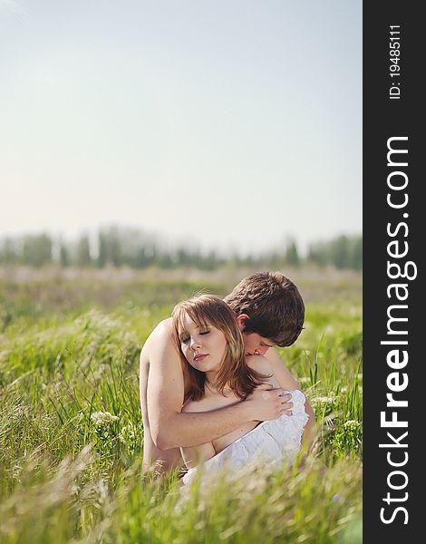 Beautiful young pair kissing and hugging on green grass