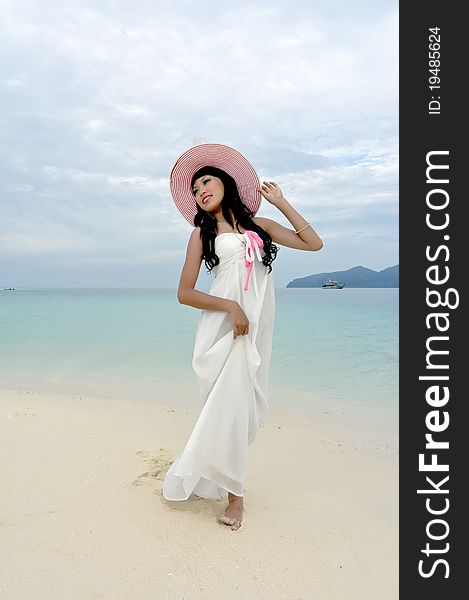 Young woman walks with hat on beach of tropical island during holiday. Young woman walks with hat on beach of tropical island during holiday