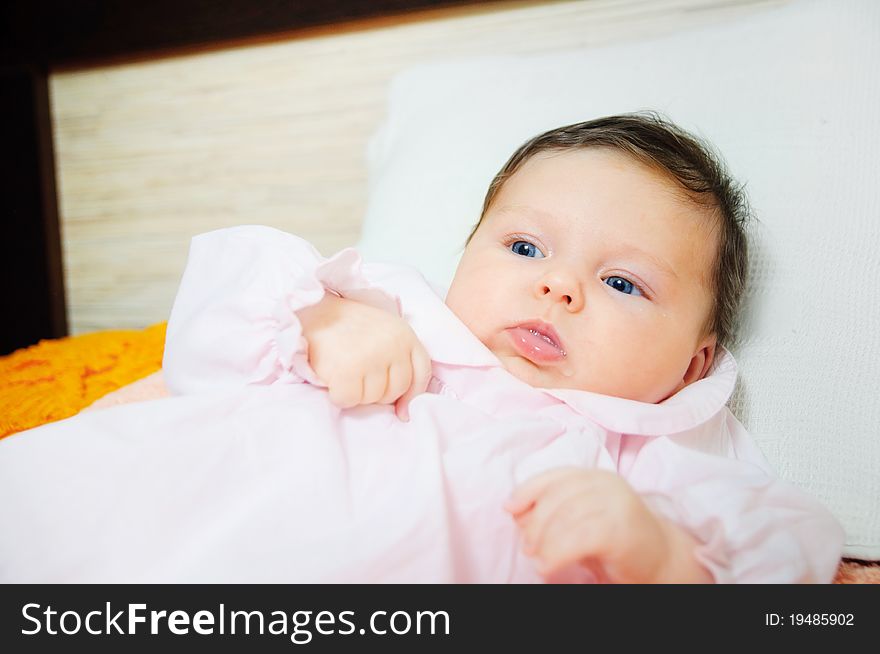 Beautiful cute baby girl is lying in a bed.