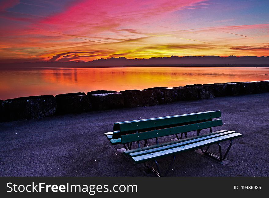 An interesting colors of early morning sky and a green bench. An interesting colors of early morning sky and a green bench