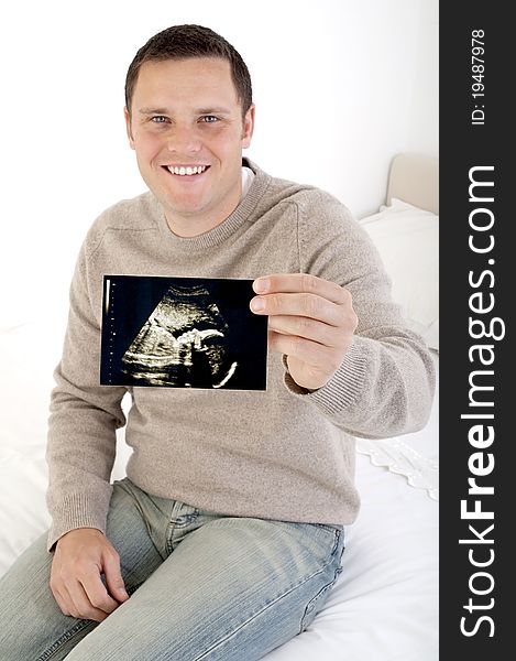 Proud dad holding ultrasound scan to camera (focus on scan)