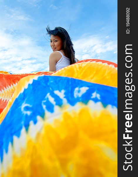 Pretty young sensuality girl is holding colorful batik sarong in front of moving boat during holiday