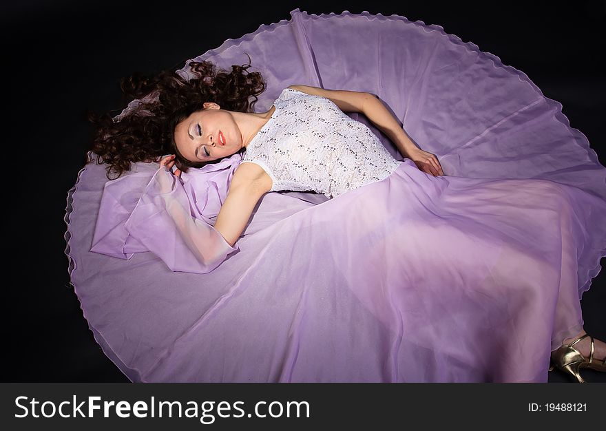 Attractive woman lying on the floor in liliac dress