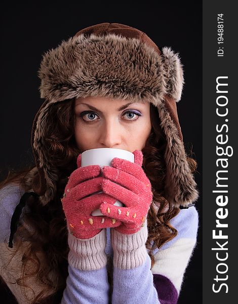 Romantic image of beautiful woman in a fur hat with a cup
