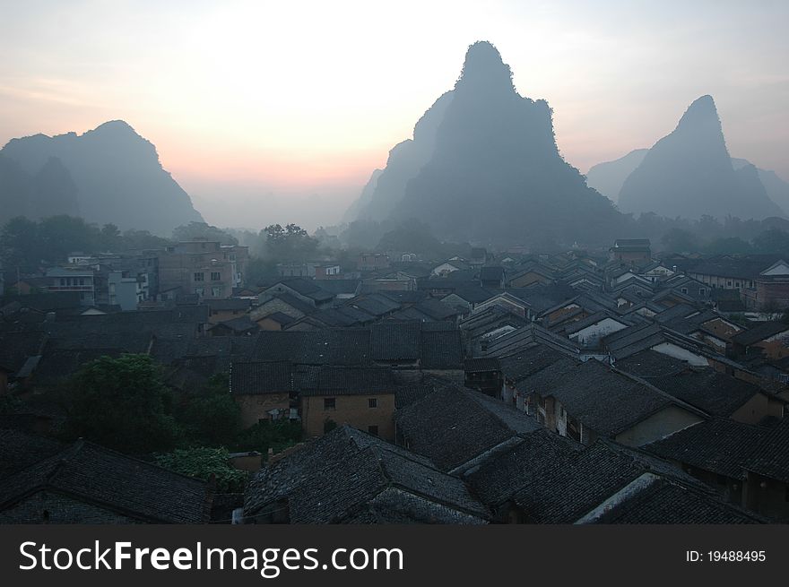 It's the sunrising of huangyao town in guangxi province china the mountains surrounding the town and the sunshine just light up the roof. It's the sunrising of huangyao town in guangxi province china the mountains surrounding the town and the sunshine just light up the roof